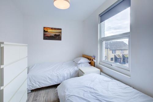 two beds in a room with a window at Pass the Keys City beach flat next to the sea sleeps up to 6 in Southend-on-Sea