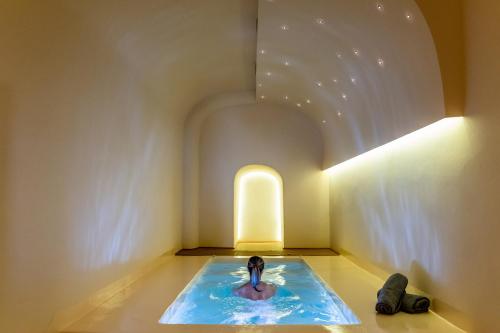 a woman in a pool in the middle of a room at Alma Libre Suites in Fira