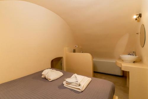 a bedroom with a bed and a sink and a tub at Alma Libre Suites in Fira