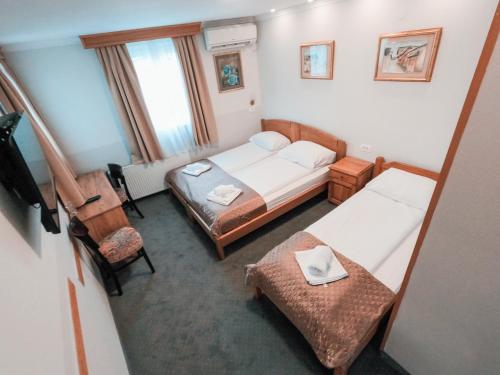 a small room with two beds and a chair at Pansion Stari Grad in Sarajevo