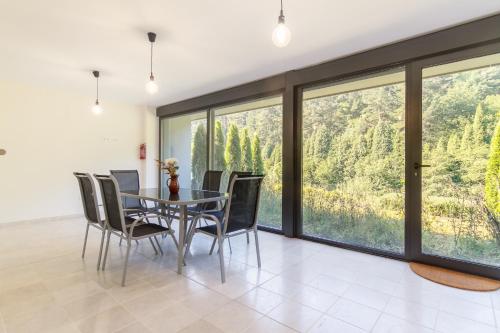 a dining room with a table and chairs and large windows at Beautiful house 15 min away from Bilbao in Llodio