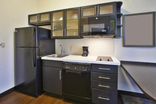 a small kitchen with a refrigerator and a sink at Candlewood Suites Morgantown-Univ West Virginia by IHG in Morgantown