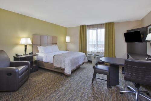 a hotel room with a bed and a desk and chair at Candlewood Suites Morgantown-Univ West Virginia by IHG in Morgantown