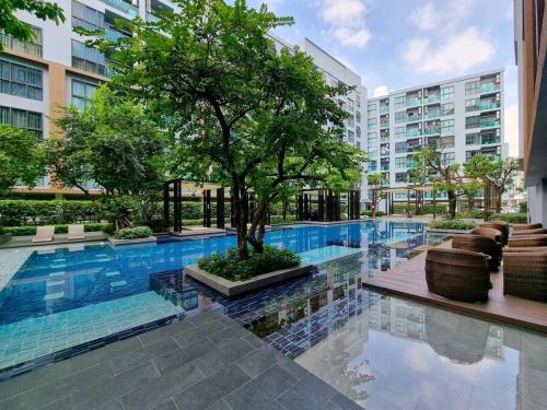 a swimming pool with a tree in the middle of a building at Studio Cozy @Sukumvit50 5mins to Bts Onnut in Bangkok