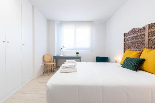 a white bedroom with a large white bed with yellow pillows at INSIDEHOME Ciudad de Valladolid in Valladolid