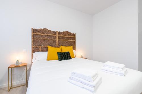 a bedroom with a large white bed with yellow pillows at INSIDEHOME Ciudad de Valladolid in Valladolid