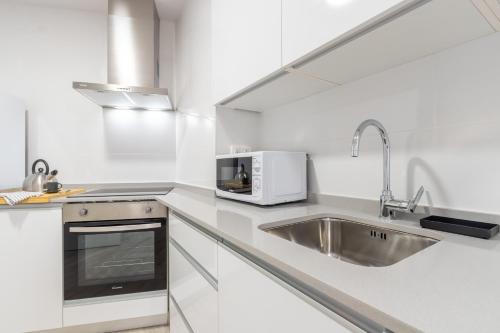 a white kitchen with a sink and a microwave at INSIDEHOME Ciudad de Valladolid in Valladolid