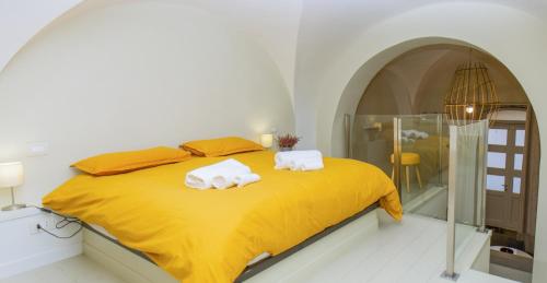 een slaapkamer met een geel bed en handdoeken bij Appartamento moderno Second House Catania 26 in Catania