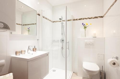 a white bathroom with a shower and a toilet at Rafael Kaiser - Apartment Cityflow in Graz