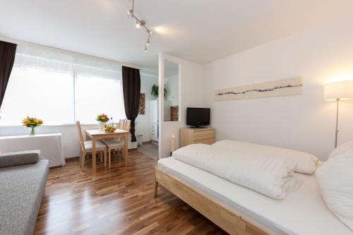 a white bedroom with a bed and a table at Rafael Kaiser - Apartment Cityflow in Graz