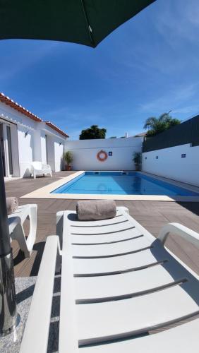 a white bench sitting on a patio next to a swimming pool at Oura Villa V2 Jacarandá in Albufeira