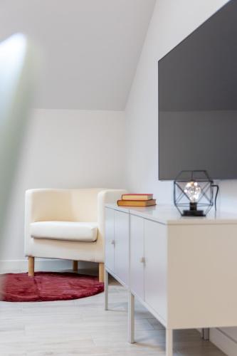 a living room with a white chair and a tv at INSIDEHOME Ciudad de Valladolid in Valladolid