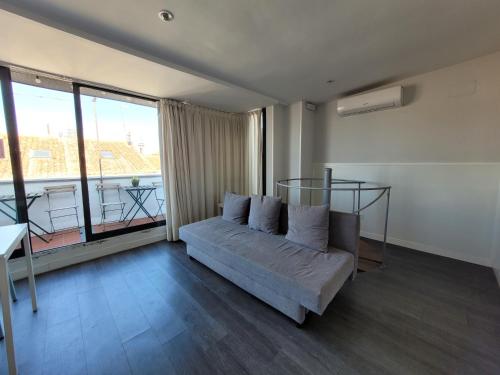sala de estar con sofá y ventanas grandes en Apartments Madrid Plaza Mayor-Cava baja, en Madrid