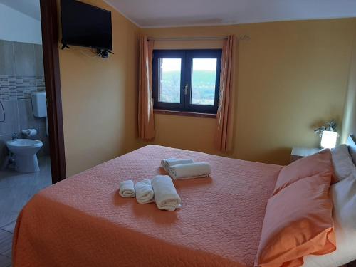 - une chambre avec un lit, des serviettes et une fenêtre dans l'établissement Agriturismo Petrosa, à Castrovillari