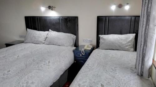 a bedroom with two beds with white sheets and a phone at Lahiff's Bay View Guest House in Spanish Point