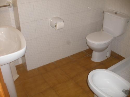 a bathroom with a white toilet and a sink at Apartamentos Can Jordi in Cala Figuera