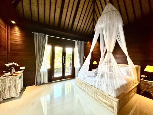 a bedroom with a bed with a mosquito net at Villa Vilah in Nusa Penida