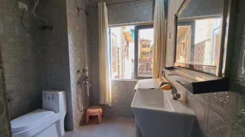 a bathroom with a sink and a toilet and a window at Sufi Khandar Home Stay in New Delhi