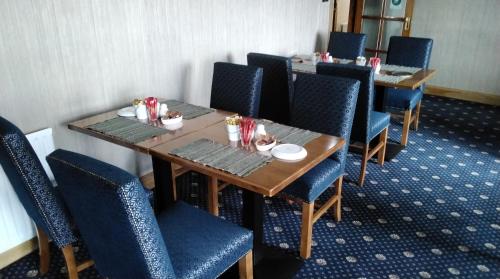 a dining room with tables and blue chairs with food on them at Lahiff's Bay View Guest House in Spanish Point