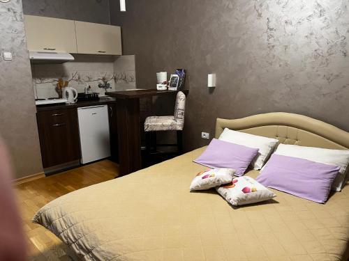 Cet appartement comprend une chambre avec un lit doté d'oreillers violets et une cuisine. dans l'établissement Apartman Studio DIAMOND, à Subotica