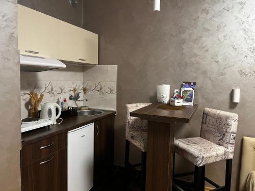 une cuisine avec un évier et un comptoir avec des chaises dans l'établissement Apartman Studio DIAMOND, à Subotica