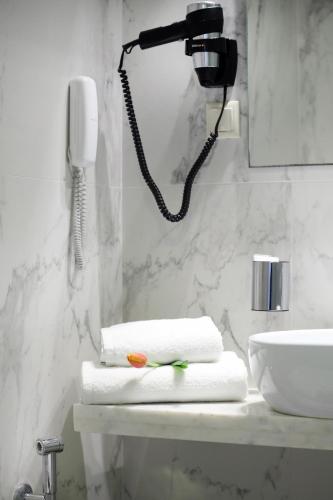 a bathroom with a phone and towels on a sink at Hotel Lefkas in Lefkada Town