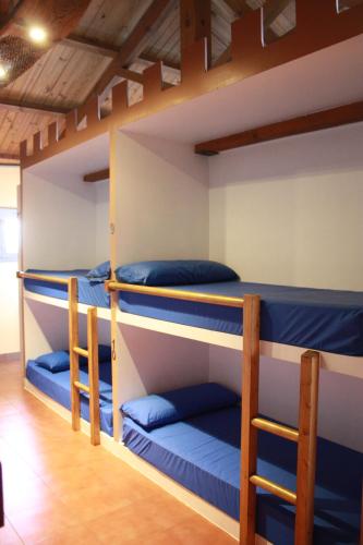 4 literas en una habitación con almohadas azules en Albergue La Casa del Camino en Valverde de la Virgen