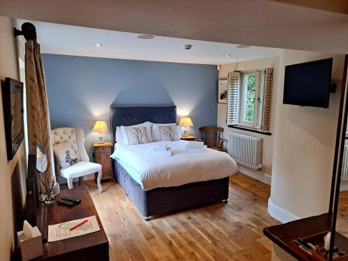 um quarto com uma cama king-size e uma cadeira em Robin Hood Farm B&B em Baslow