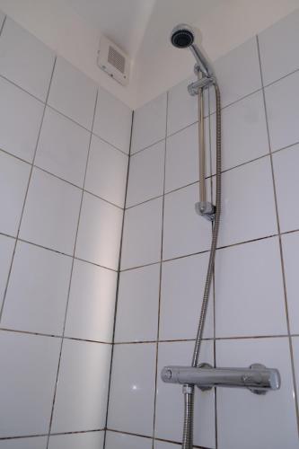 a shower with a shower head on a white tiled wall at Eelhouse private studio in Amsterdam