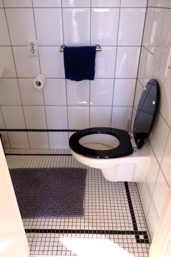 a bathroom stall with a toilet with a black seat at Eelhouse private studio in Amsterdam