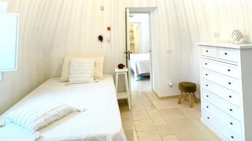 Habitación blanca con cama y espejo en Trulli di Pone, en Cozzana