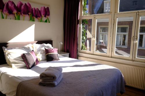 a bedroom with a bed and a window with purple tulips at Eelhouse private studio in Amsterdam
