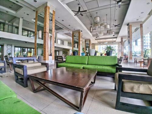 ein Wohnzimmer mit einem grünen Sofa und einem Tisch in der Unterkunft Modern Condo Apt in Flair Tower South, Mandaluyong in Manila