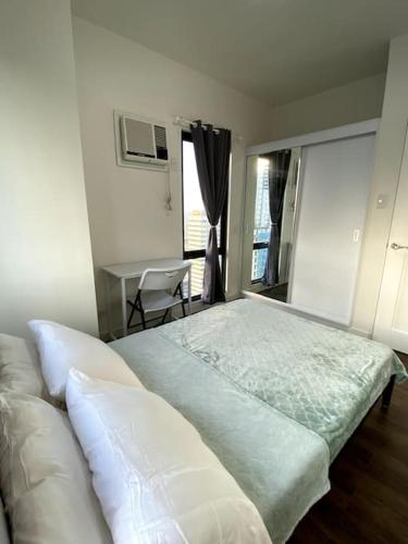 a bedroom with a large bed with a desk and a window at Modern Condo Apt in Flair Tower South, Mandaluyong in Manila