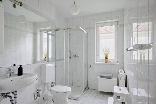 ein weißes Bad mit einer Dusche, einem WC und einem Waschbecken in der Unterkunft Ferienwohnung Hafeneck Moba-Travel in Lübeck