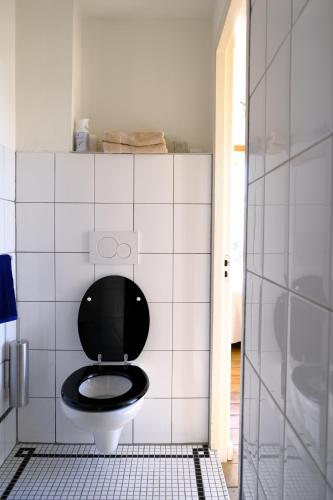 een badkamer met een toilet en een zwarte stoel bij Studio Eelhouse in Amsterdam