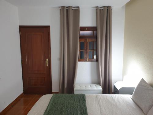 a bedroom with a bed and a door and a window at Cantinho dos Montes in Vila Real