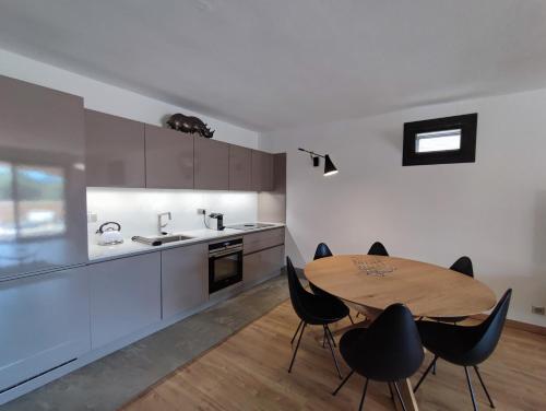 eine Küche mit einem Holztisch und schwarzen Stühlen in der Unterkunft Appartement confortable pour 6 personnes avec piscine privée in Lecci
