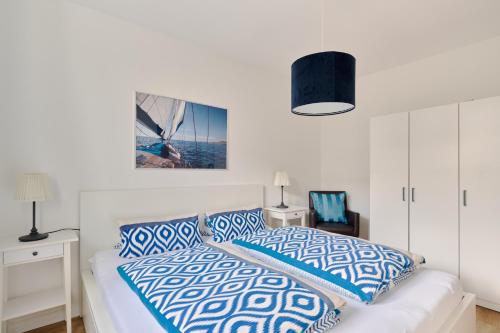 a bedroom with a bed with blue and white pillows at Ferienwohnung Sonnendeck Moba-Travel in Priwall