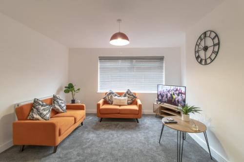 a living room with two orange couches and a tv at Skipton Lodge in Billingham