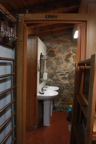 a bathroom with a sink and a stone wall at Albergue La Casa del Camino in Valverde de la Virgen