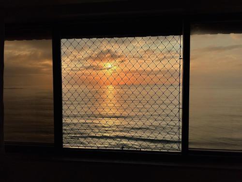 a view of the ocean through a window with a fence at Praia da Costa, SUNRISE STAY in Vila Velha