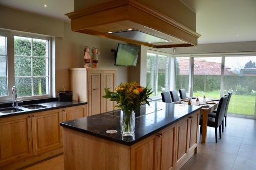 a kitchen with a large island with a vase of flowers at Vakantiewoning Scheewege met zwemvijver en jacuzzi in Wingene