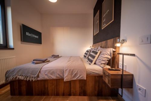 a bedroom with a bed with a wooden headboard at BlackWood Apartment Zlatibor in Zlatibor