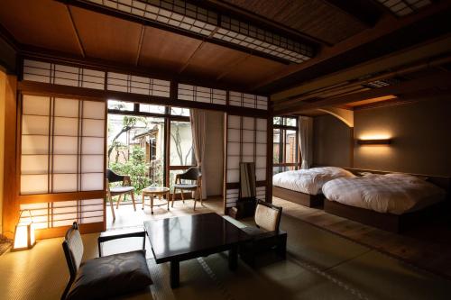 豐岡的住宿－城崎温泉 旅館 つばき乃 - Kinosaki Onsen Ryokan Tsubakino，卧室配有一张床和一张桌子及椅子