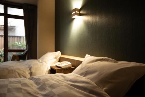 a bedroom with two beds and a phone on a table at 城崎温泉 旅館 つばき乃 - Kinosaki Onsen Ryokan Tsubakino in Toyooka