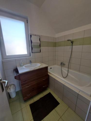 baño con lavabo, bañera y ventana en Parti nyaraló, en Balatonfüred