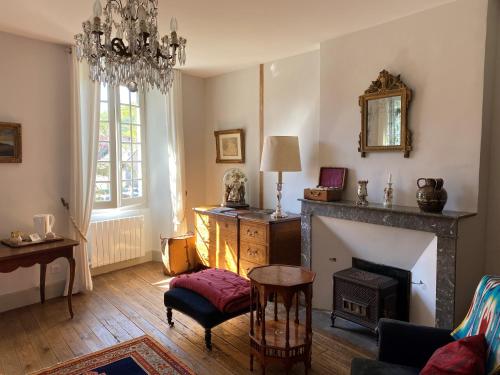 a living room with a fireplace and a chandelier at Le Clos Rodolphe in Beaulieu-sur-Dordogne