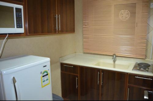 a kitchen with a sink and a white refrigerator at المواسم الاربعة للاجنحه الفندقية in Al Jubail