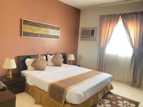 Un dormitorio con una cama grande y una ventana en المواسم الاربعة للاجنحه الفندقية, en Al Jubail